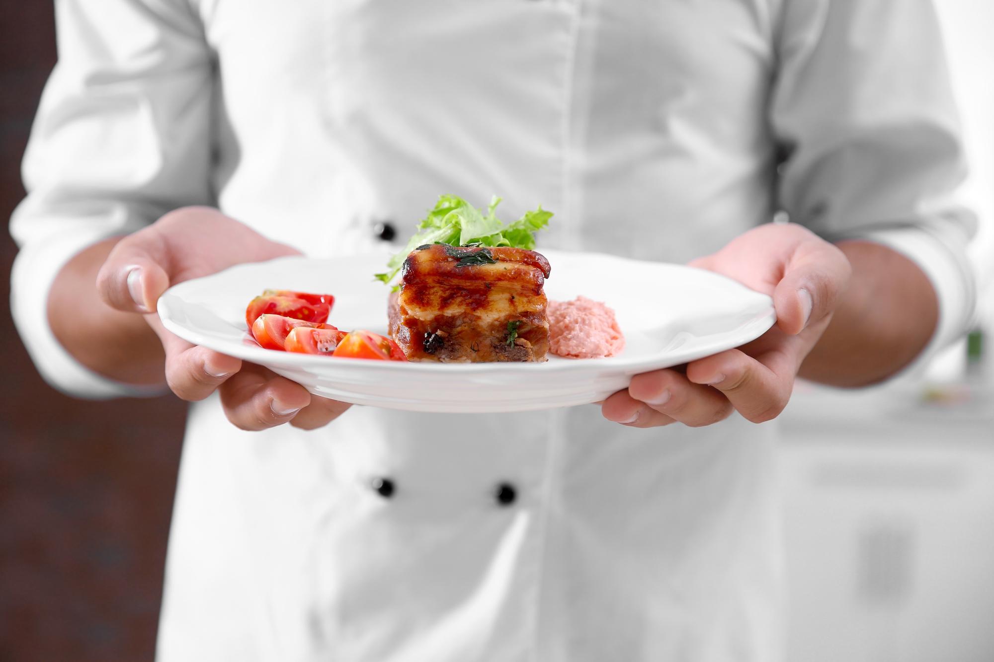 chef plating a modern dish in warm kitchen